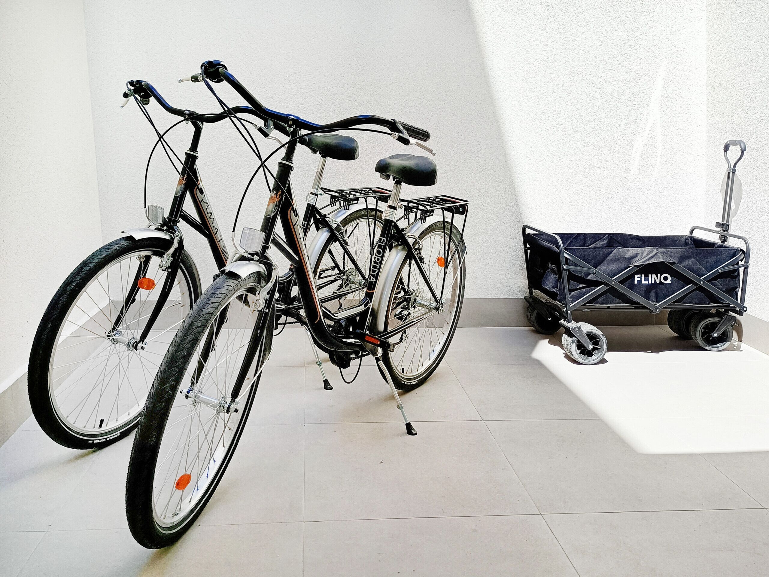 A bicycle with a basket and a FLINQ branded trolley.