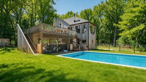 Una casa a due piani in legno con piscina, immersa nel verde.