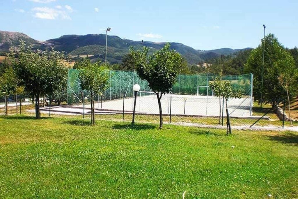 Ein Tennisplatz, umgeben von B äumen, mit Bergen im Hintergrund.