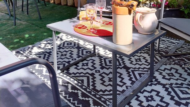 Une terrasse extérieure avec une table dressée pour un repas, entourée de murs en pierre et de verdure.