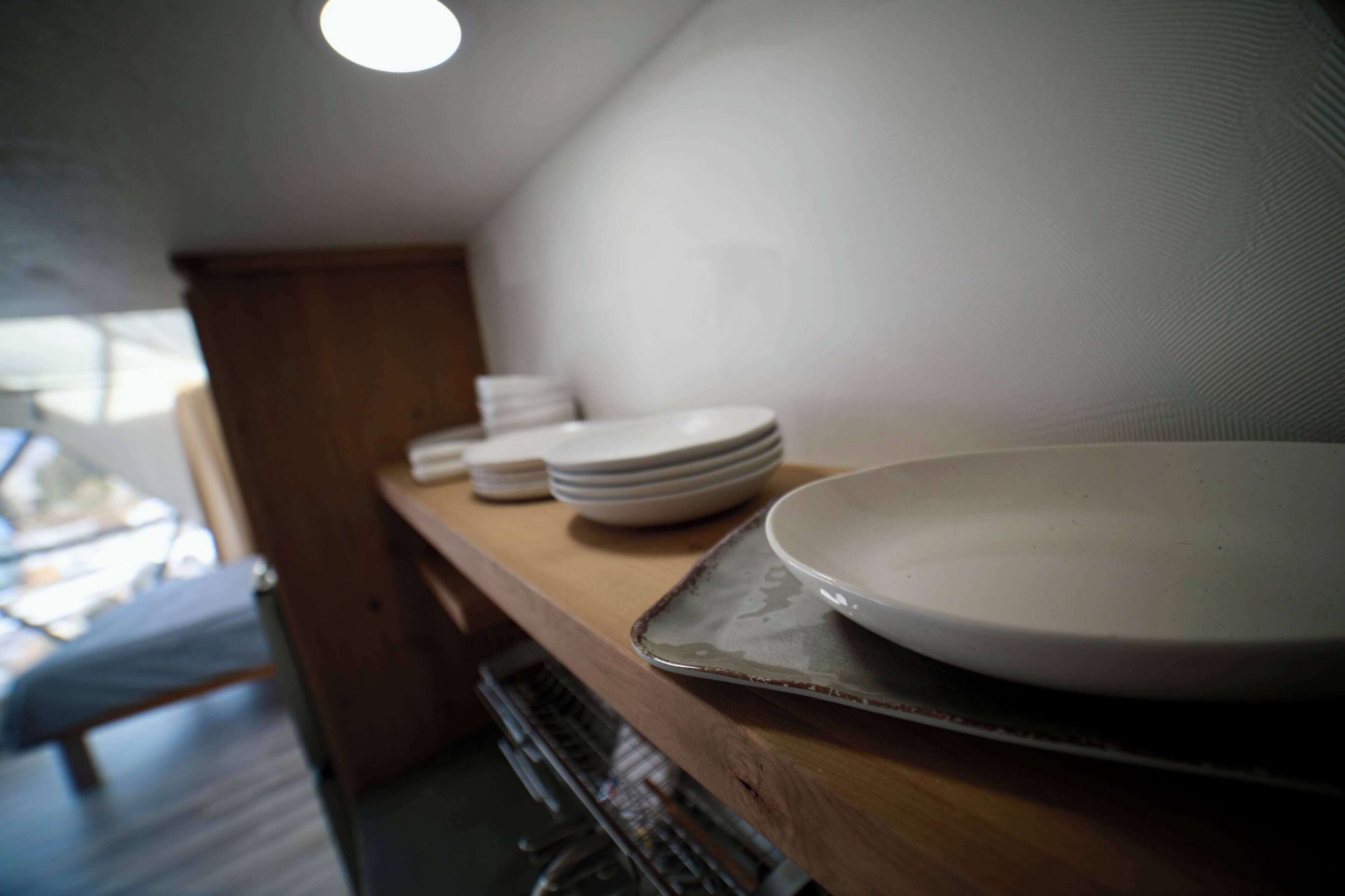 Un comptoir de cuisine avec une pile d’assiettes blanches et une grande assiette isolée.