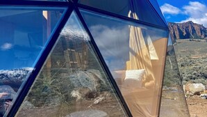 En geodætisk kuppelstruktur med en klar himmel og et bjerglandskab i baggrunden.