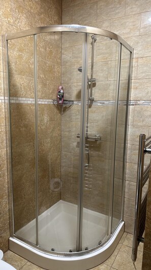 A glass-enclosed shower stall with a handheld showerhead and a handheld soap dispenser. - Charming 1-bed Studio in London (London)