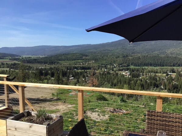 A wooden deck with a view of a forested valley and mountains.