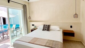 A hotel room with a bed, ceiling fan, bedside tables, and a view of the pool area. - HOTEL CARACOL ISLA MUJERES (Isla Mujeres)