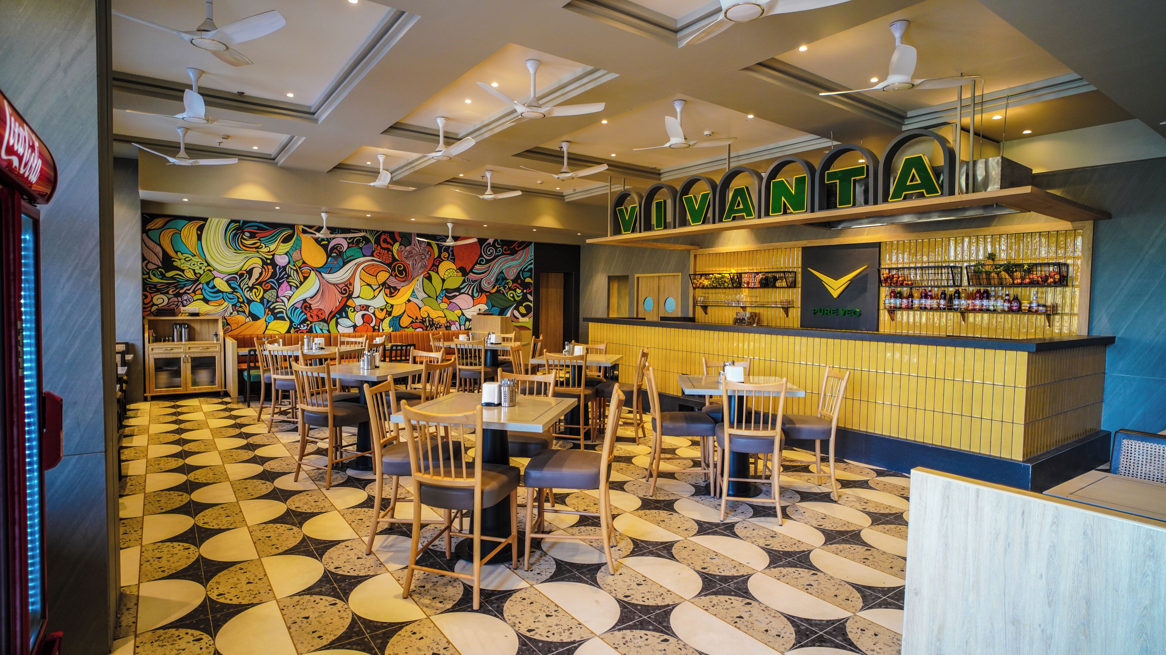 A restaurant interior with a colorful mural, a bar area, and a patterned floor.