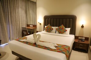 A hotel room with a large bed, a desk, and a chair. - Hotel Le Vivanta (Vasai)