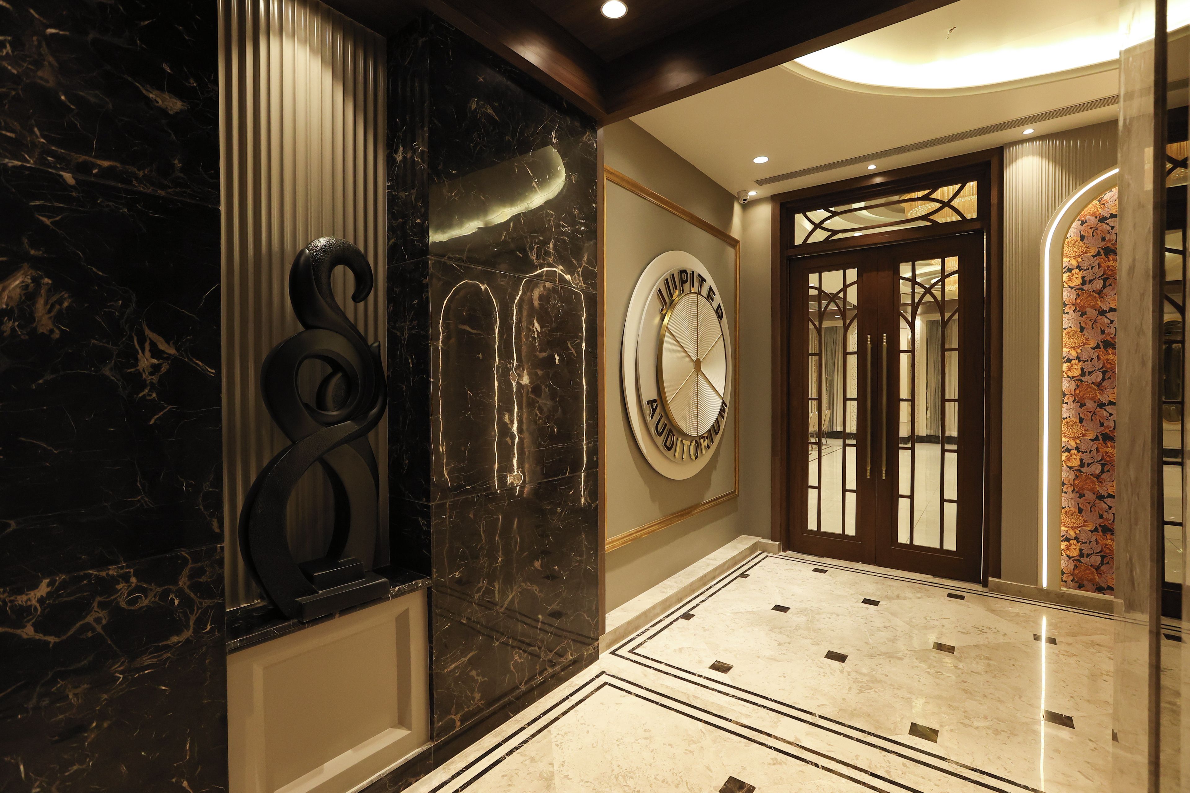 A hallway with marble flooring, a wall-mounted clock, and a door with a floral pattern.