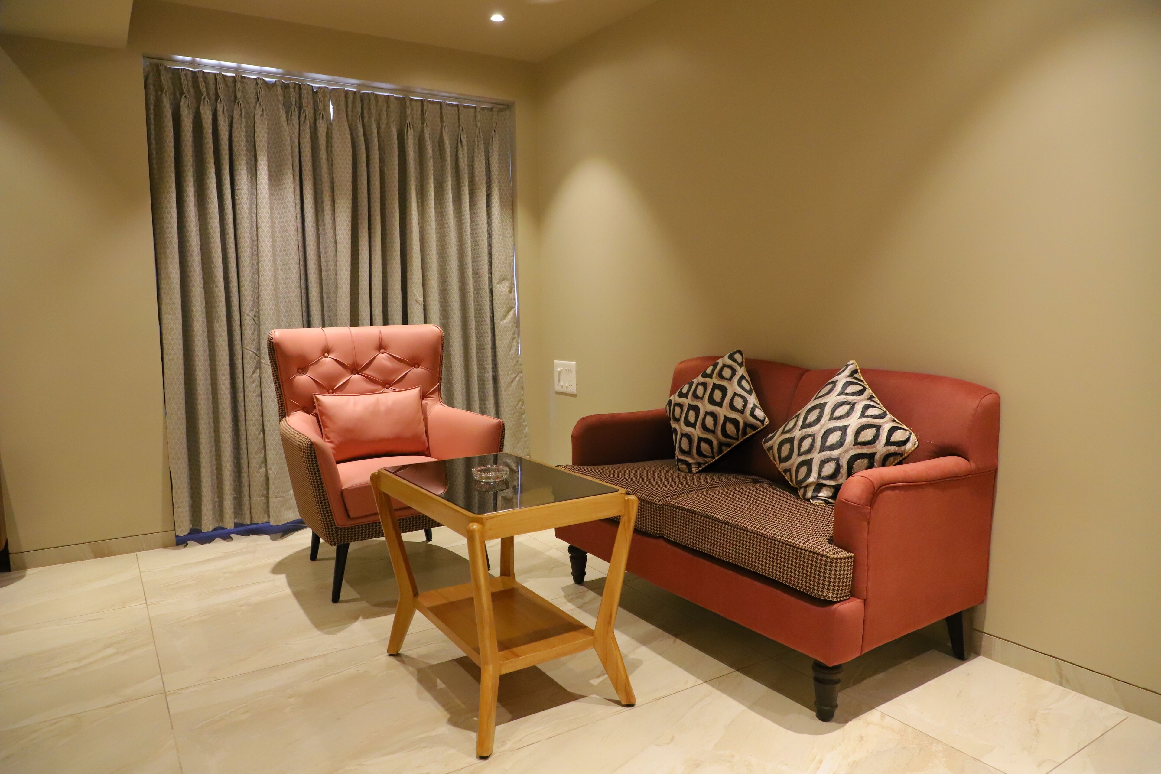 A living room with a red sofa, a tufted armchair, and a glass-top coffee table.