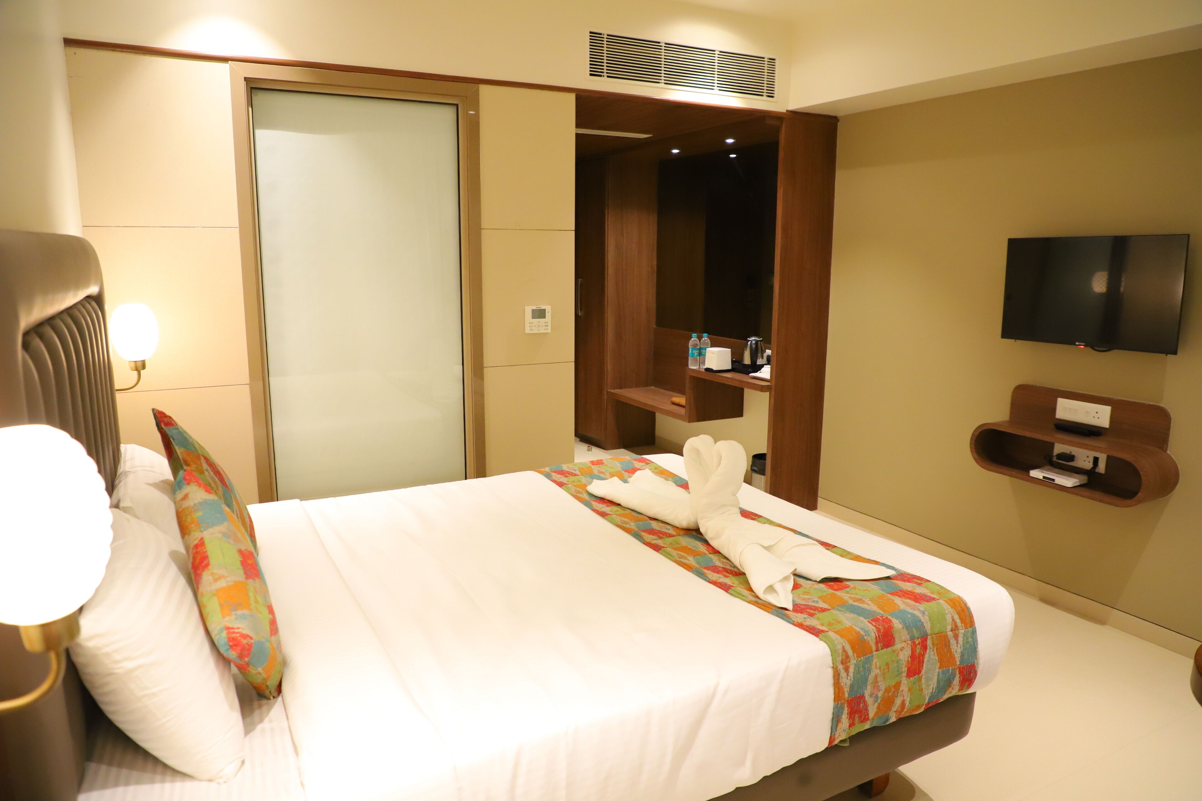 Een hotelkamer met een bed, een televisie, een kledingkast en een plank met toiletartikelen.