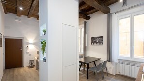 A modern kitchen with a dining area, wooden beams, a refrigerator, and a window with curtains. - Navona Modern apartment (Rome)