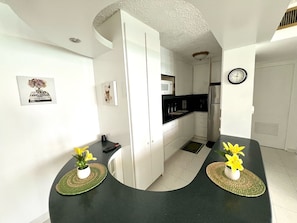 Enjoy cooking in this well-equipped kitchen with white cabinetry, black countertops, and stainless steel appliances.