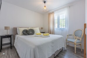 Une chambre à coucher avec un lit, des tables de chevet, une chaise et une fenêtre avec des rideaux.