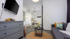 A modern living room with a grey sofa, a small round table with a plant, and a grey dresser. - Modern flat with WiFi, air conditioning, 850 metre beach (Crikvenica)