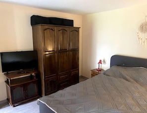 Cozy retreat with a large bed, wooden wardrobe, and flat-screen TV.