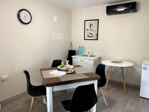 Cozy retreat with a dining table and comfortable seating for four, a wall-mounted air conditioner, and a stylish cabinet with a mirror.