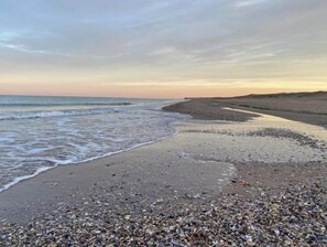 Enjoy a serene beach experience with gentle waves lapping onto the shore.