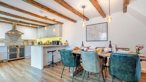 Una cocina moderna con vigas de madera, una isla central y un comedor con sillas.