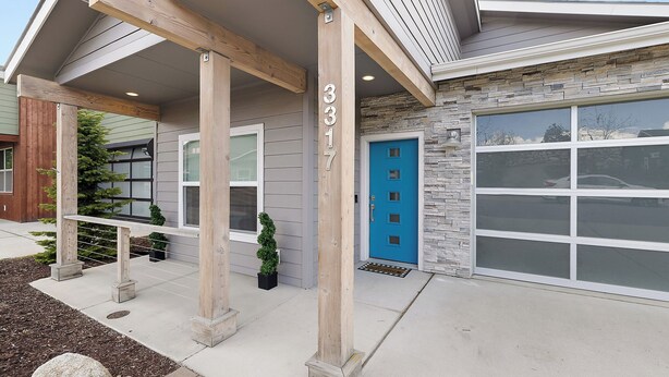 A modern house with a stone facade, a blue door, and a garage. - Luxury Gated Coeur d’Alene Home Near Golf, Riverstone & Downtown. (Coeur d'Alene)