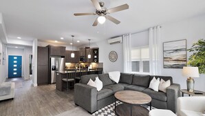 A modern living room with a sectional sofa, a coffee table, and a ceiling fan. - Luxury Gated Coeur d’Alene Home Near Golf, Riverstone & Downtown. (Coeur d'Alene)