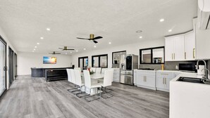 A modern kitchen with white cabinets, stainless steel appliances, and a dining area with white chairs. - Naples Oasis: Heated Pool, Gazebo, Grill Retreat (Naples)