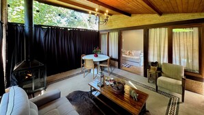 Una habitació acollidora amb una llar de foc, un sofà, una taula amb objectes decoratius i vistes a l'exterior.