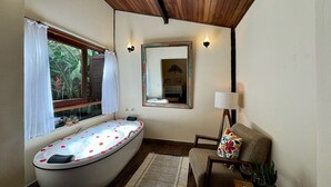 Une salle de bain avec une baignoire sur pieds, une fenêtre avec des rideaux, un miroir, une lampe et une chaise.