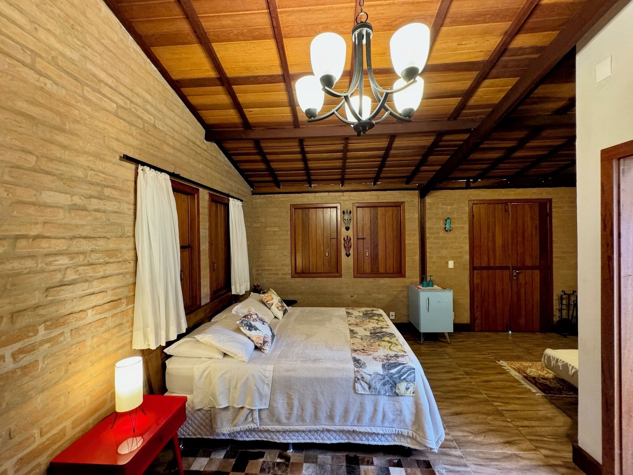A bedroom with a large bed, wooden wardrobe, and a chandelier.