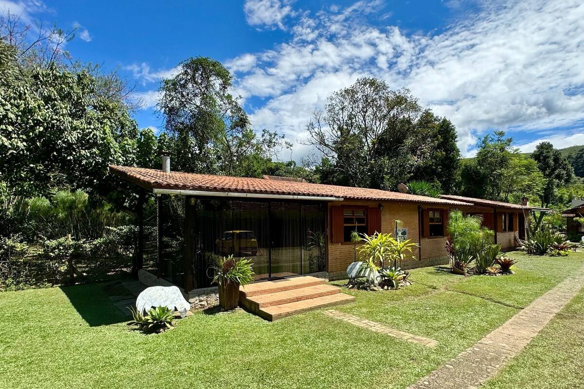 Una casa de un piso con techo de tejas, un porche cubierto y un césped bien cuidado.