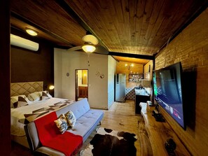 Una habitación acogedora con sofá, televisión y techo de madera.