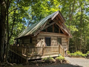 A rustic cabin with a wooden deck and a metal roof, surrounded by trees. - The Blue Bird Suite at Hawthorn Haven- Upper Level (Waynesville)