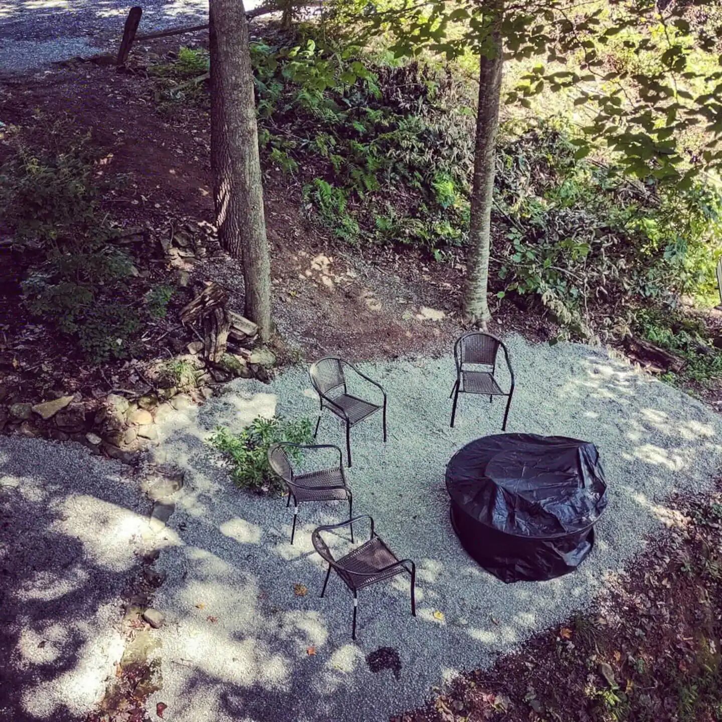 Eine gepflegte Schotterterrasse mit vier Metallstühlen und einem schwarzen Müllsack.