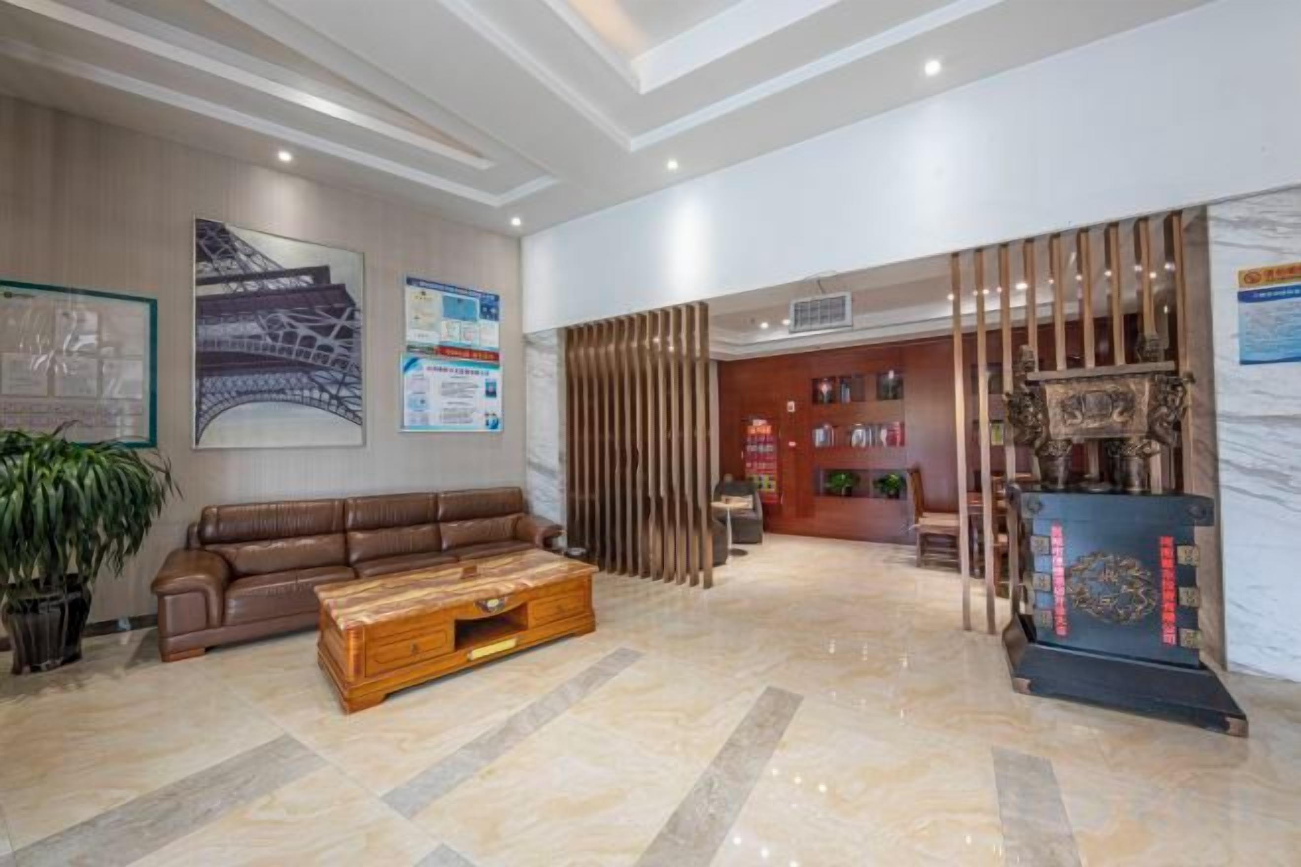 Um hall amplo com um sofá de couro, uma mesa de centro de madeira e uma receção decorada com objetos.
