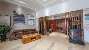 Um hall amplo com um sofá de couro, uma mesa de centro de madeira e uma receção decorada com objetos.