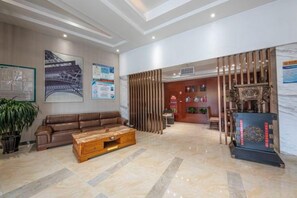 A spacious lobby with a leather sofa, a wooden coffee table, and a reception desk with decorative items. - Jinxuan Hotel (Zhengzhou South Third Ring Road) (Zhengzhou)