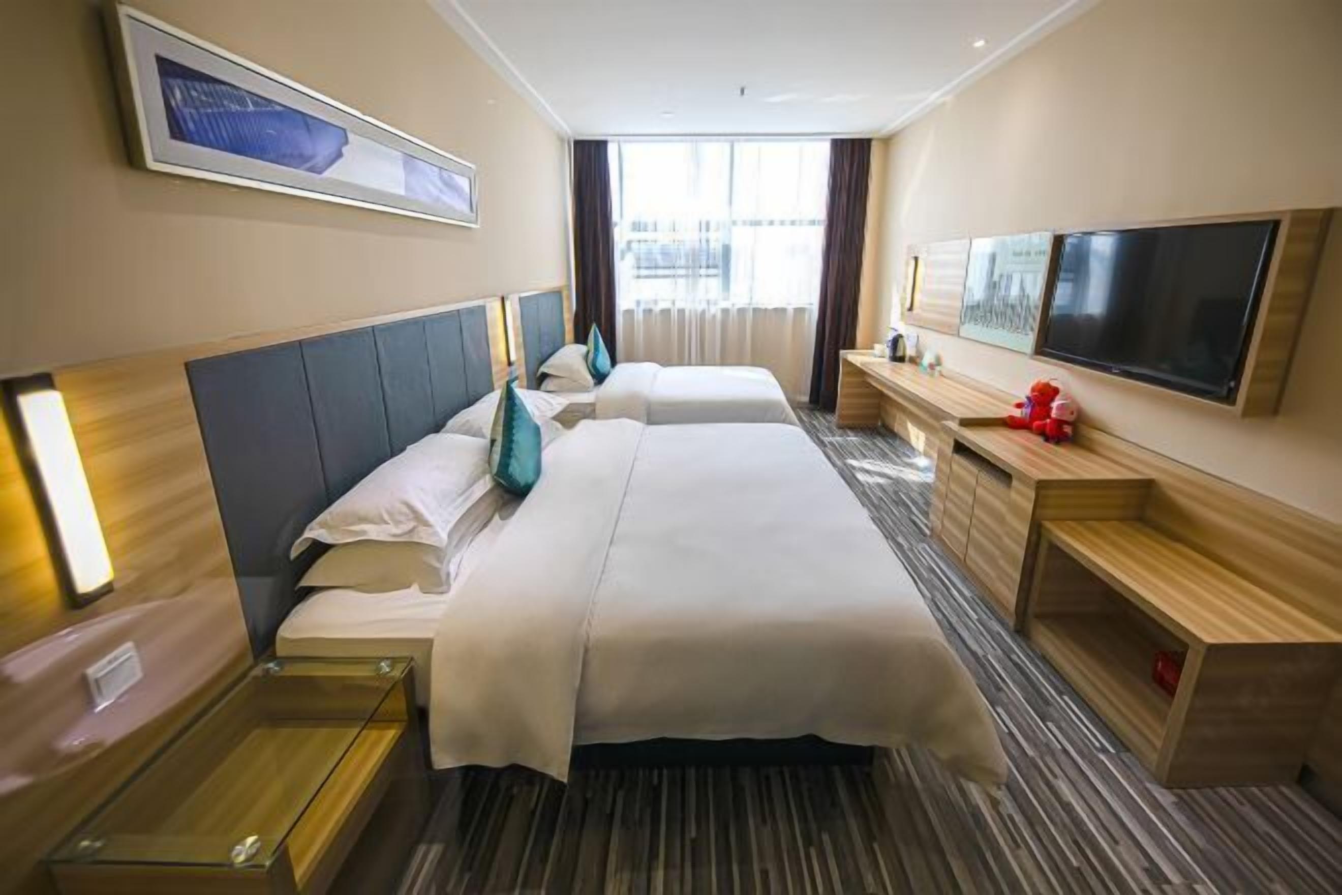 Une chambre d’hôtel avec deux lits, une télévision, un bureau et une fenêtre avec des rideaux.