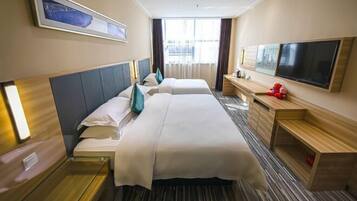 Quarto de hotel com duas camas, televisão, escrivaninha e janela com cortinas.