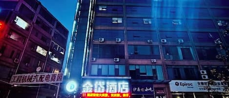 Un hotel con varios pisos, amplias ventanas y señalización que indica que es un hotel.
