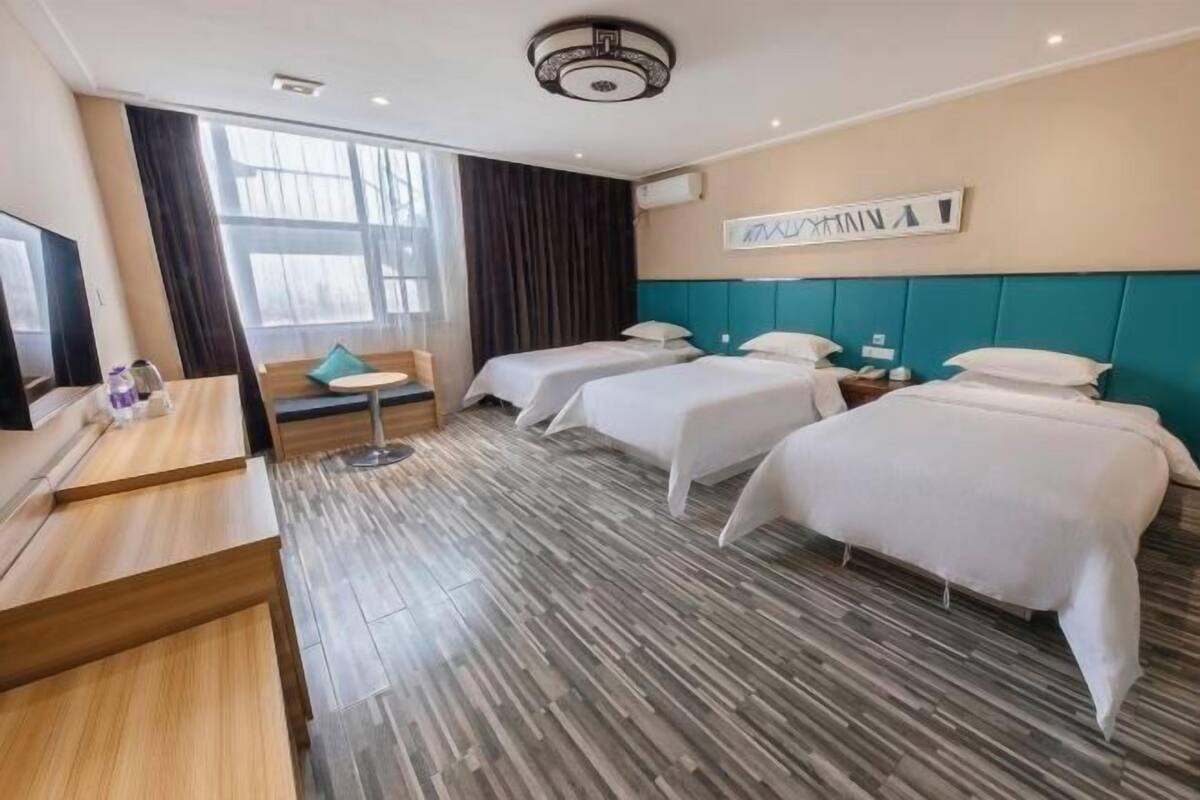 Ein Hotelzimmer mit zwei Betten, einem Schreibtisch, einem Stuhl und einem großen Fenster.