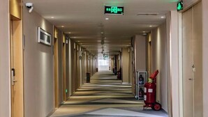 Ein Hotelgang mit Feuerlöscher und Notausgangsschild.