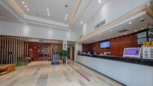 Ein Hotel-Empfangsbereich mit Marmorboden, einer Rezeption, einem Fernseher und einer Holzwand.
