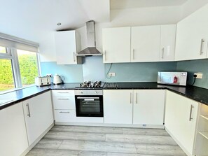 Huis, uitzicht op tuin | Privékeuken | Een kinderstoel, schoonmaakproducten