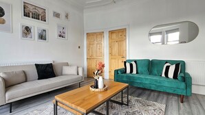 A living room with a beige sofa, a green sofa, a wooden coffee table, and a mirror on the wall. - Spacious Haven with Free Parking (Glasgow)