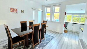 A dining area with a table and chairs, a patterned rug, and a view of the outdoors through large windows. - Spacious Haven with Free Parking (Glasgow)