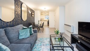 A modern living room with a grey sofa, a coffee table, and a flat-screen TV. - London Oasis Apartment Escape (London)