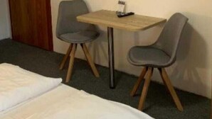Habitación de hotel con dos camas, un escritorio, dos sillas, un televisor y una puerta.