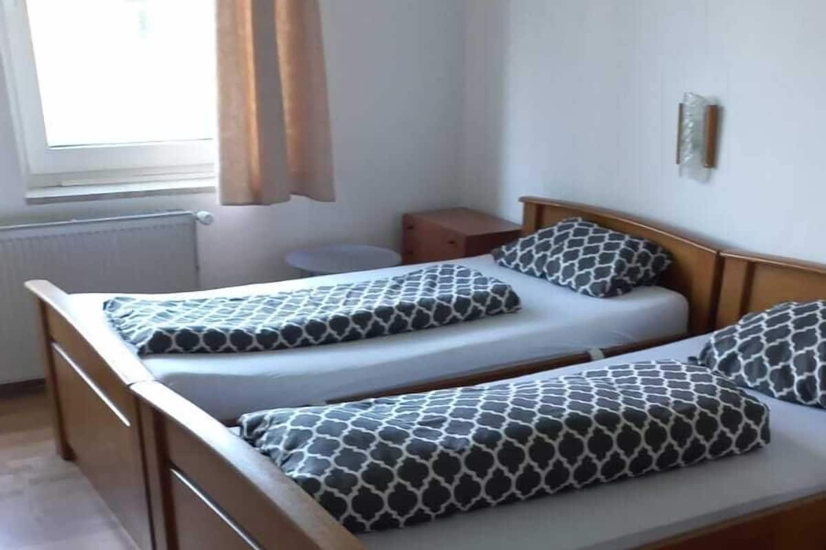 Un lit double avec des coussins à motifs, une tête de lit en bois et une table de chevet.