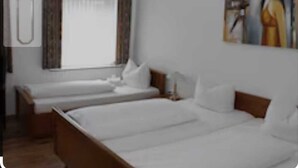 Una habitación de hotel con dos camas individuales, un ventanal con cortinas y un cuadro en la pared.