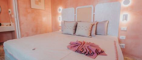 A bedroom with a bed, bedside lamps, a wall-mounted air conditioner, and a framed picture on the wall.
