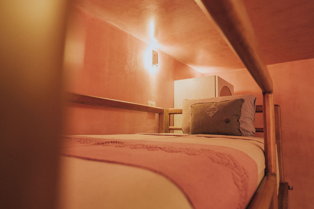 A bunk bed with a headboard and a bedside table with a lamp.